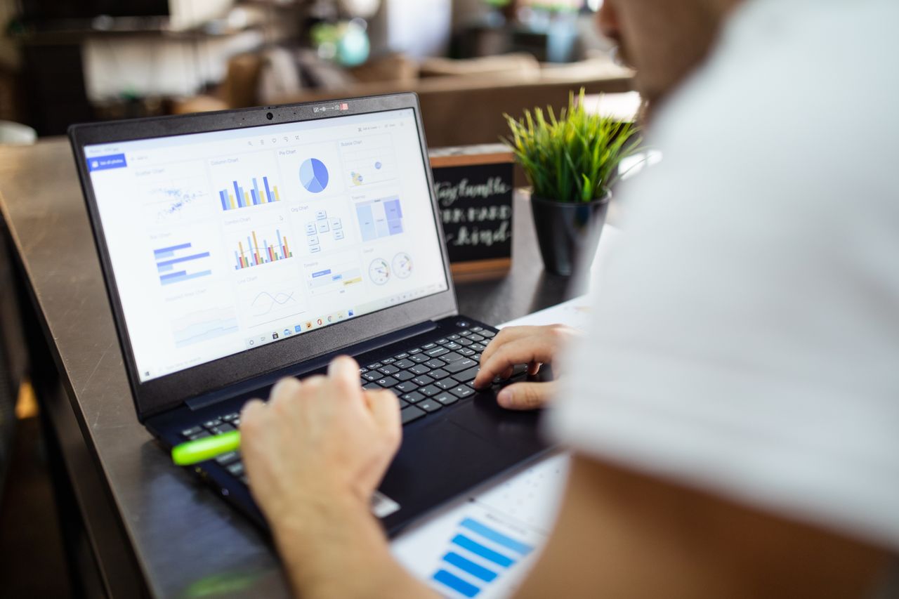 services-04 Focused business analysis with charts and graphs on a laptop in a modern office setting.